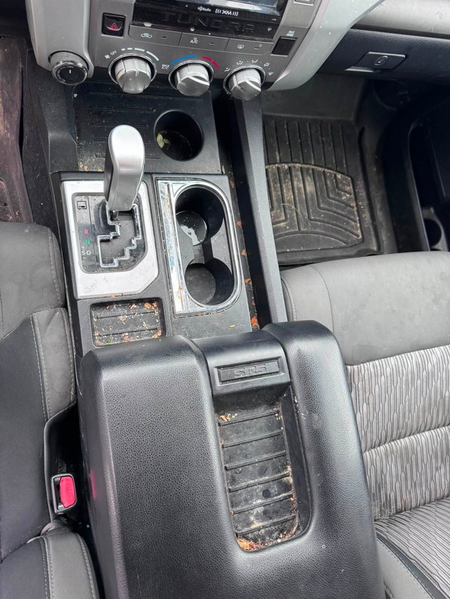 Truck centre console and cup holders before cleaning, with crumbs and dirt in the tray and around the shifter.